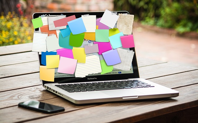 Image of a laptop covered with a huge mess of post it notes. The screen of the laptop is fully covered.